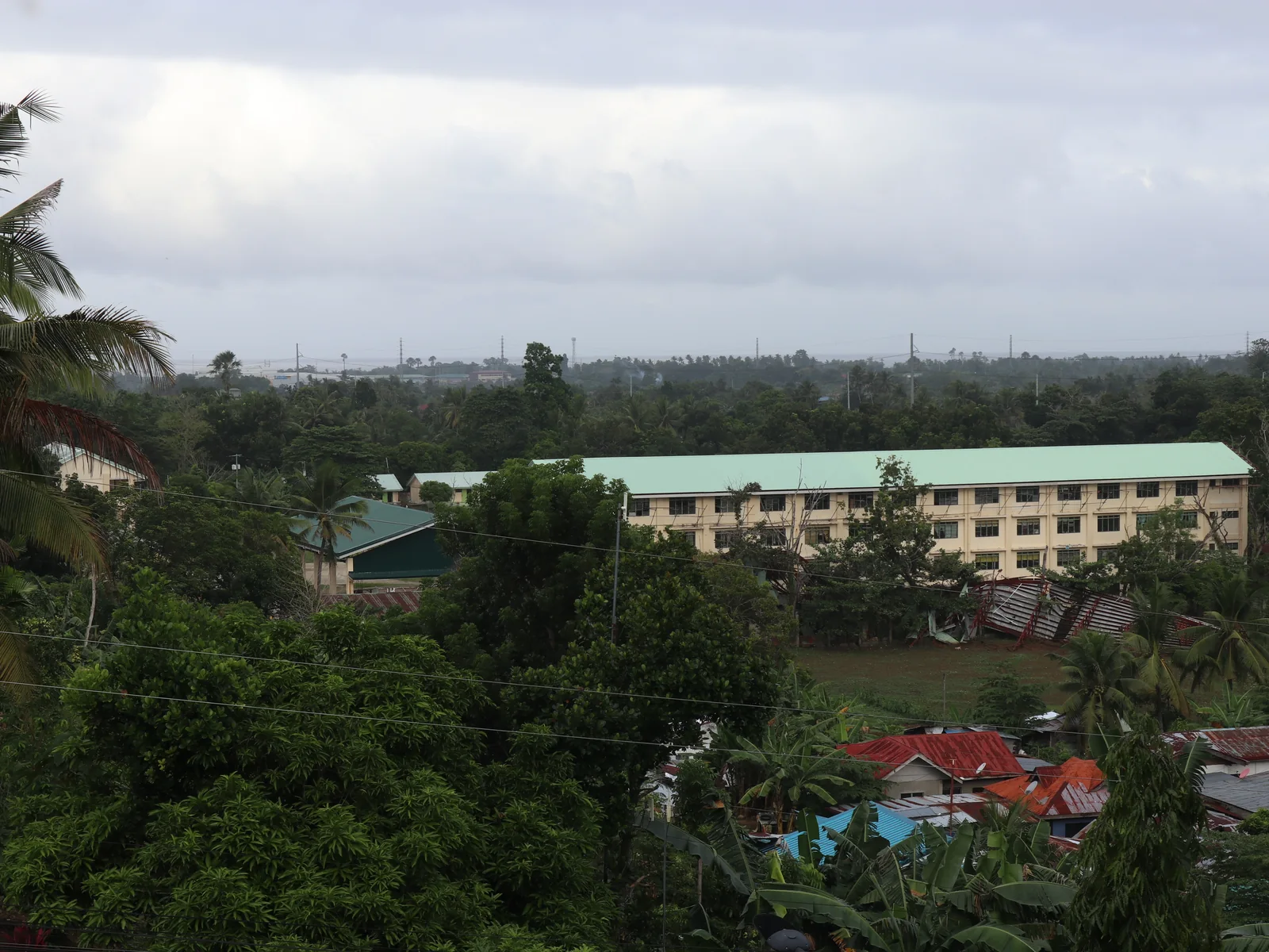 Toledo City seen from Ilihan: trees, rooftops and a long green-roofed building, with the hills beyond.
